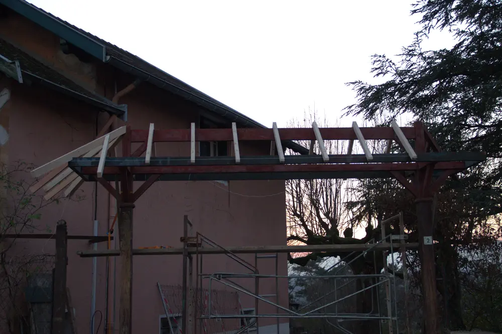 Pose des tavaillons en bois sur la toiture d’un auvent de portail traditionnel