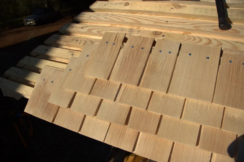 Pose des tavaillons en bois sur la toiture d’un auvent de portail traditionnel