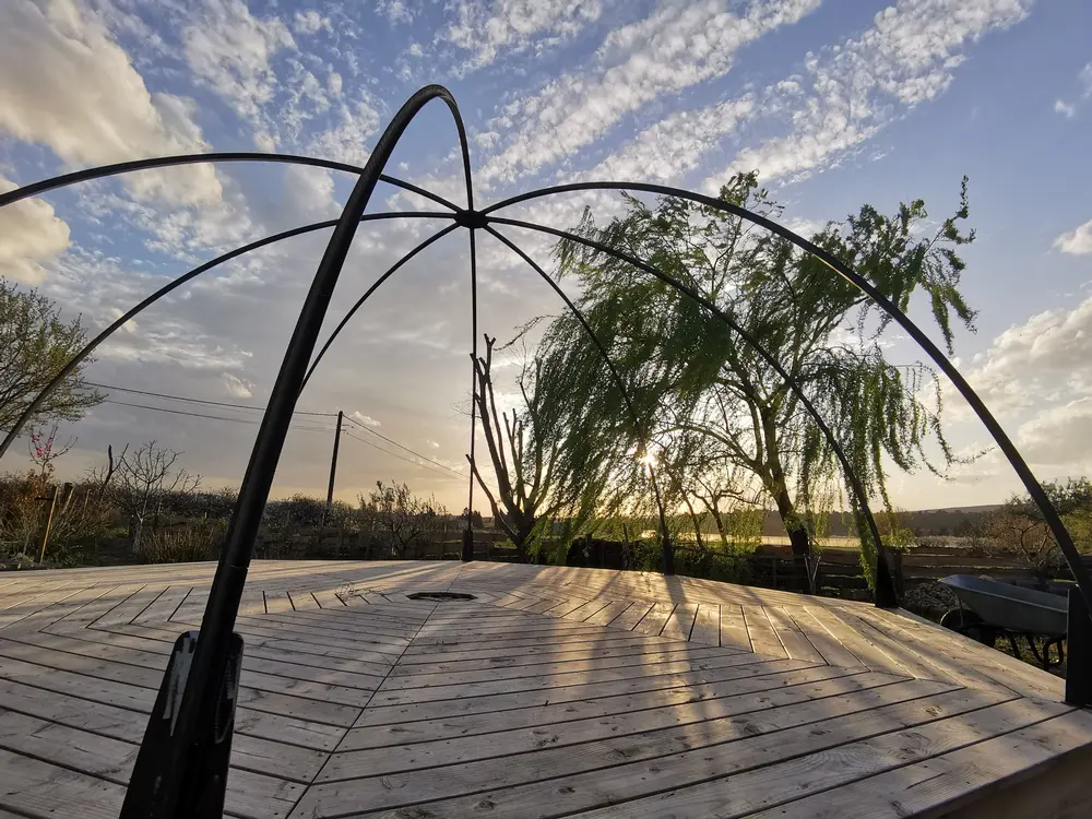 Terrasse couverte par la structure arrondie de l’Igloo Végétal, vue sur le jardin potager