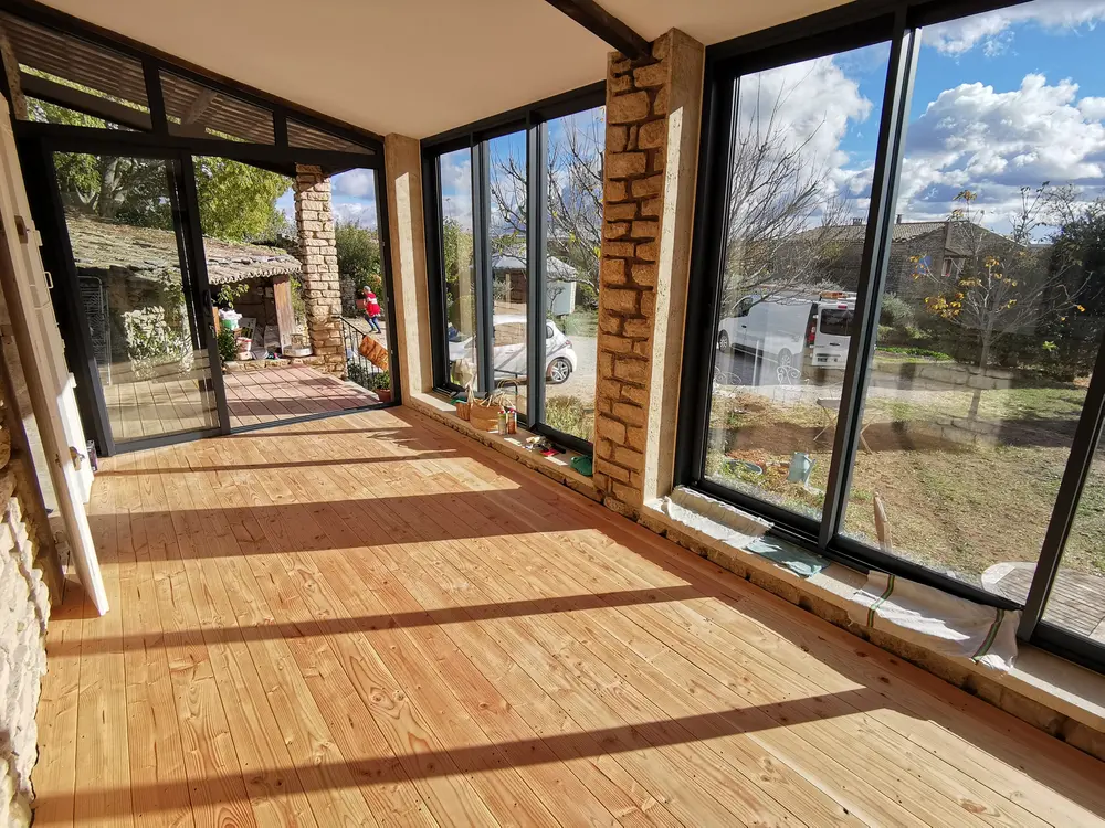 Vue intérieure de la véranda en bois, structure en pierre apparente